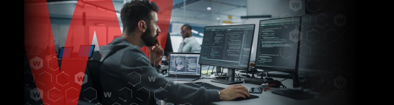 Man working in an open office with a large red W behind him