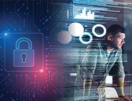 Man leaning on a desk in front of screens with code and graphs on them