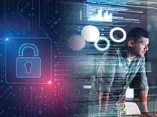 Man leaning on a desk in front of screens with code and graphs on them